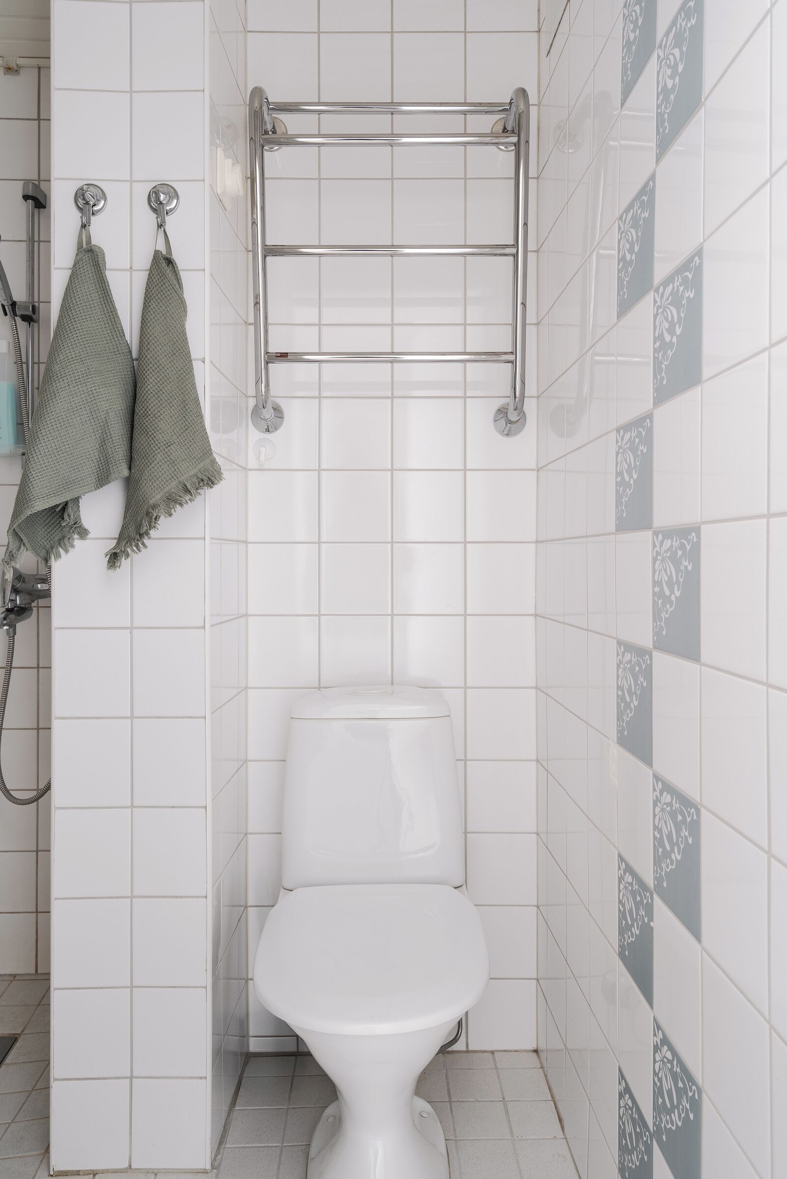 Un baño con inodoro blanco, toallero con dos toallas y ducha.