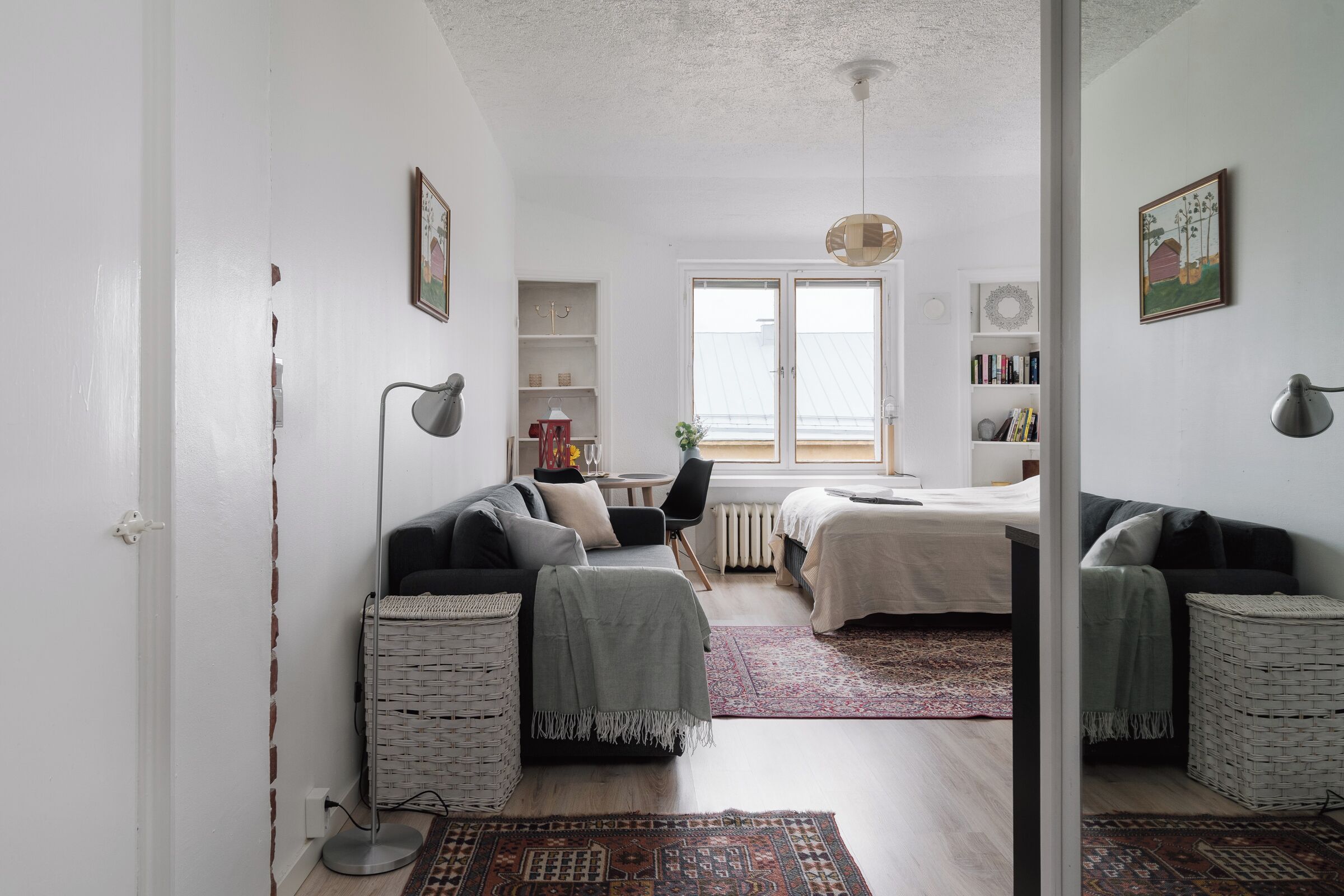 Une chambre moderne et bien éclairée, dotée d’un grand lit, d’un coin salon avec un canapé et des fauteuils, et d’un coin repas avec une table et des chaises.
