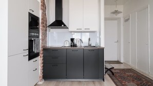 Une cuisine de taille réduite, dotée d’une hotte noire, de meubles blancs et d’un tapis à motifs.