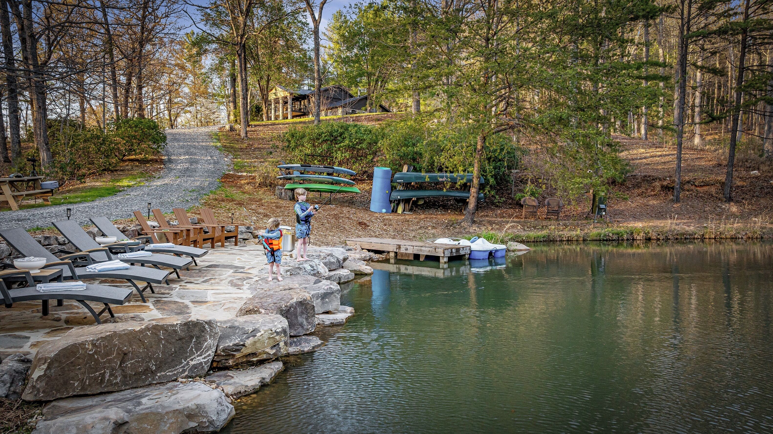 A lakeside setting with lounge chairs, a dock, and kayaks.