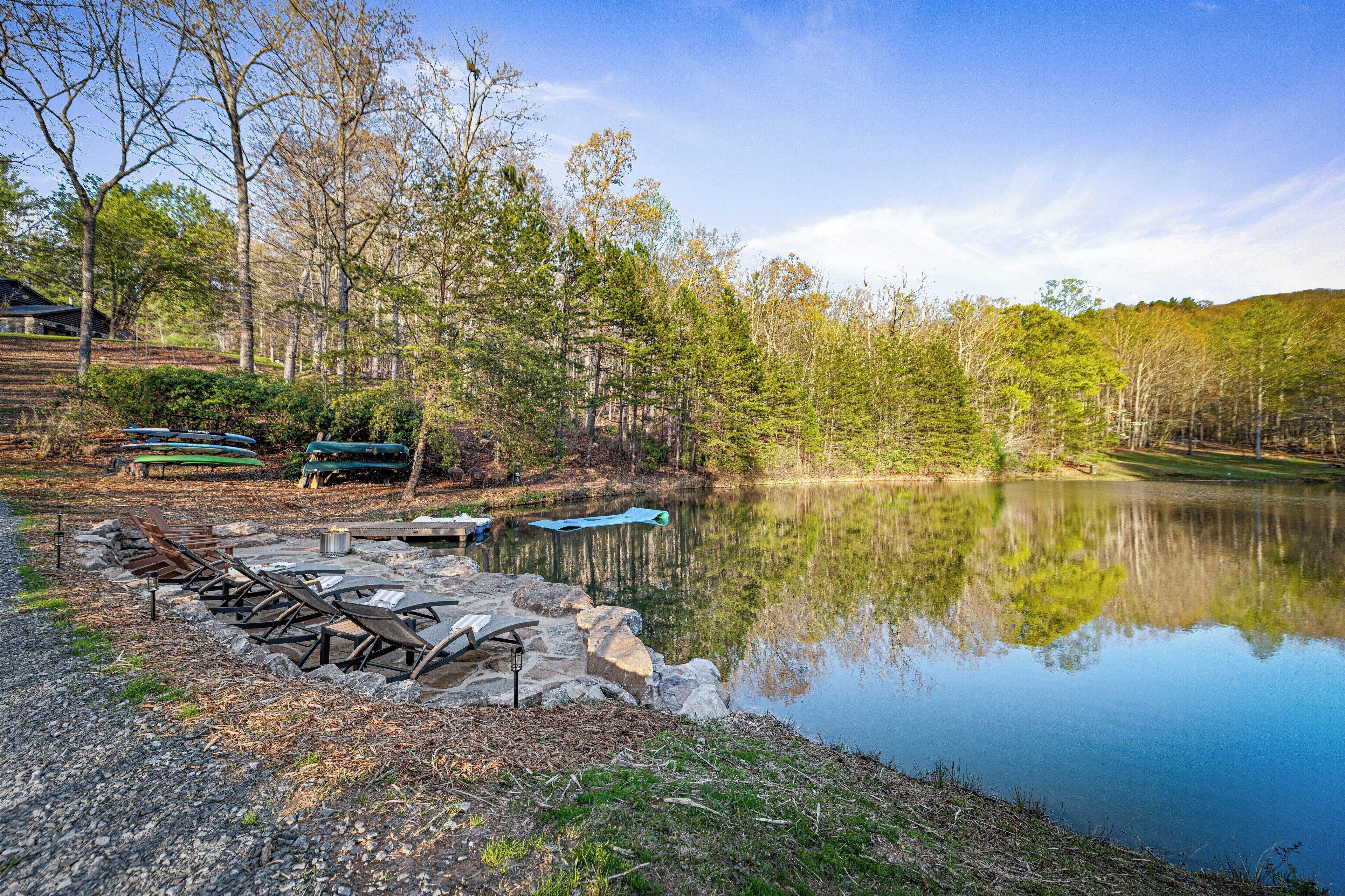 A serene lakeside setting with a row of lounge chairs and a picnic table by the water's edge.