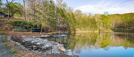 A serene lakeside setting with a row of lounge chairs and a picnic table by the water's edge.