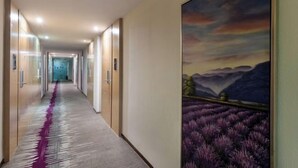 A hallway with a long corridor, doors on both sides, and a large painting of a landscape on the right wall. - Lavande Hotels (Guangzhou Fangcun Huadiwan) (Guangzhou)