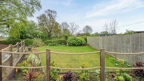 A wooden deck with rope barriers, a grassy area with various plants, and a wooden fence in the background. - Willow Lodge 1 - UK48642 (Taunton)
