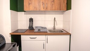 Une cuisine compacte dotée d’un meuble supérieur en bois, d’un évier en acier inoxydable et d’un égouttoir à vaisselle.