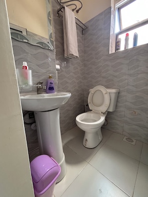 Features a pedestal sink and a toilet, with a window offering a view of the sky.