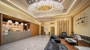 Eine Hotelhalle mit Empfangstresen, einer Sitzecke und einem Chandelier.