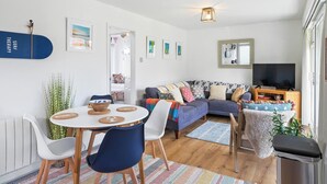 A modern living room with a sofa, TV, and dining area. - 2 bedroom accommodation in Newquay (Newquay)