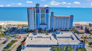 Un grand hôtel composé de plusieurs immeubles de grande hauteur, avec un parking et une plage en arrière-plan.