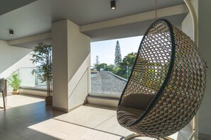 A modern interior with a hanging chair, potted plants, and a view through large windows. - Babi by the Sea by Atlantic Holiday (Funchal)