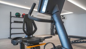 A stationary bike with a digital display, a wall-mounted rack with exercise balls, and a bench. - Babi by the Sea by Atlantic Holiday (Funchal)