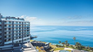 Un hotel moderno con diversi piani, una piscina sul tetto e vista sull'oceano.