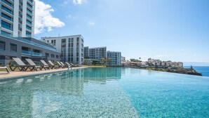 A modern hotel with a large infinity pool, lounge chairs, and a view of the ocean. - Babi by the Sea by Atlantic Holiday (Funchal)