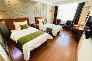 A hotel room with two beds, a desk, a chair, and a small table.