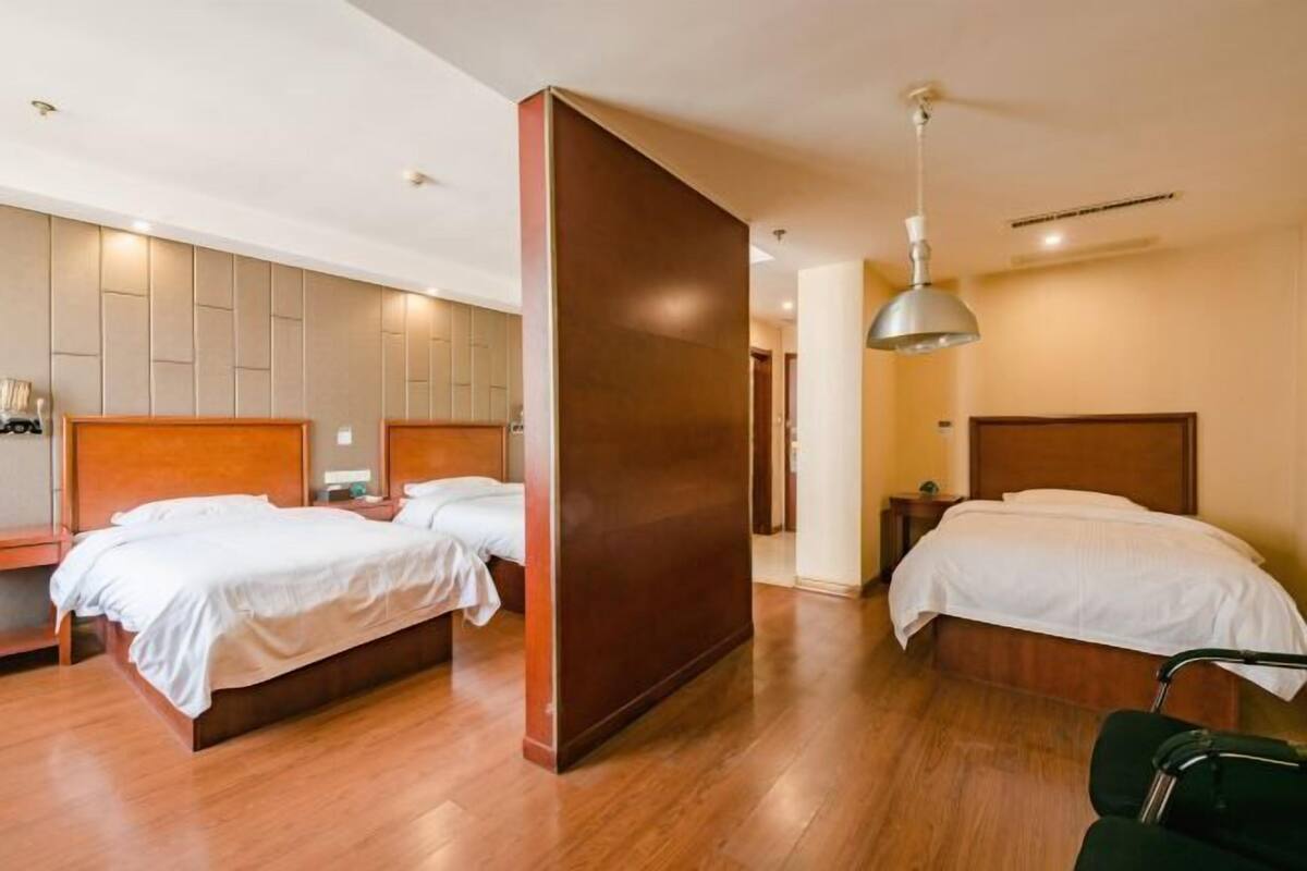 A hotel room with two beds, wooden flooring, and a modern design.