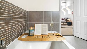 A bathroom with a bathtub, a book, a candle, and a tray with cookies. - Olympic House - Spacious house for a weekend with friends (Hinckley)