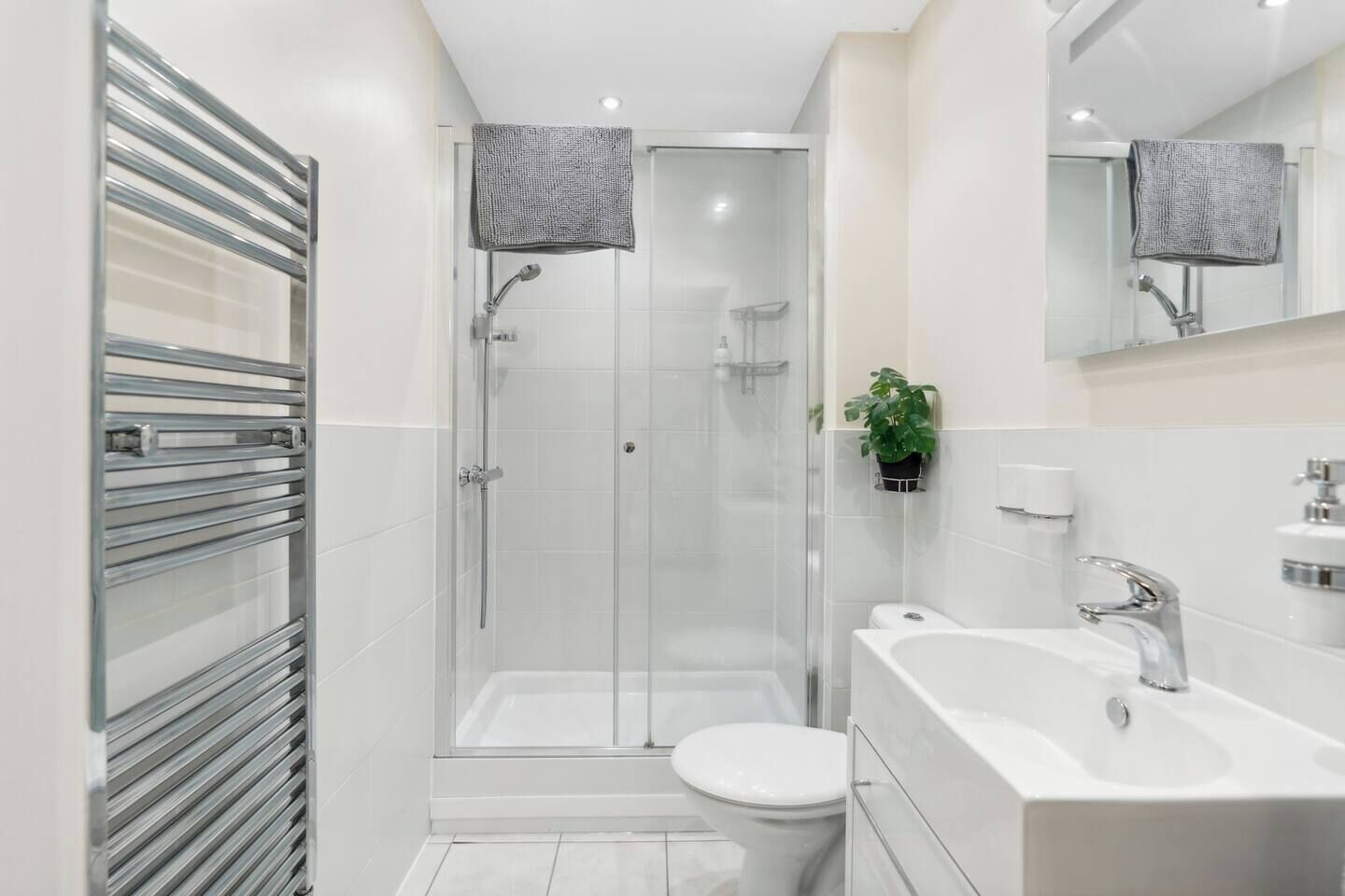 Ein modernes Badezimmer mit einer Duschkabine, einer Toilette und einem Waschbecken mit Spiegel darüber.