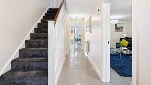 A staircase with carpeted steps and white railings leading to a hallway with a tiled floor. - Olympic House - Spacious house for a weekend with friends (Hinckley)
