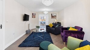 A modern living room with a chandelier, a sofa set, and a coffee table. - Olympic House - Spacious house for a weekend with friends (Hinckley)