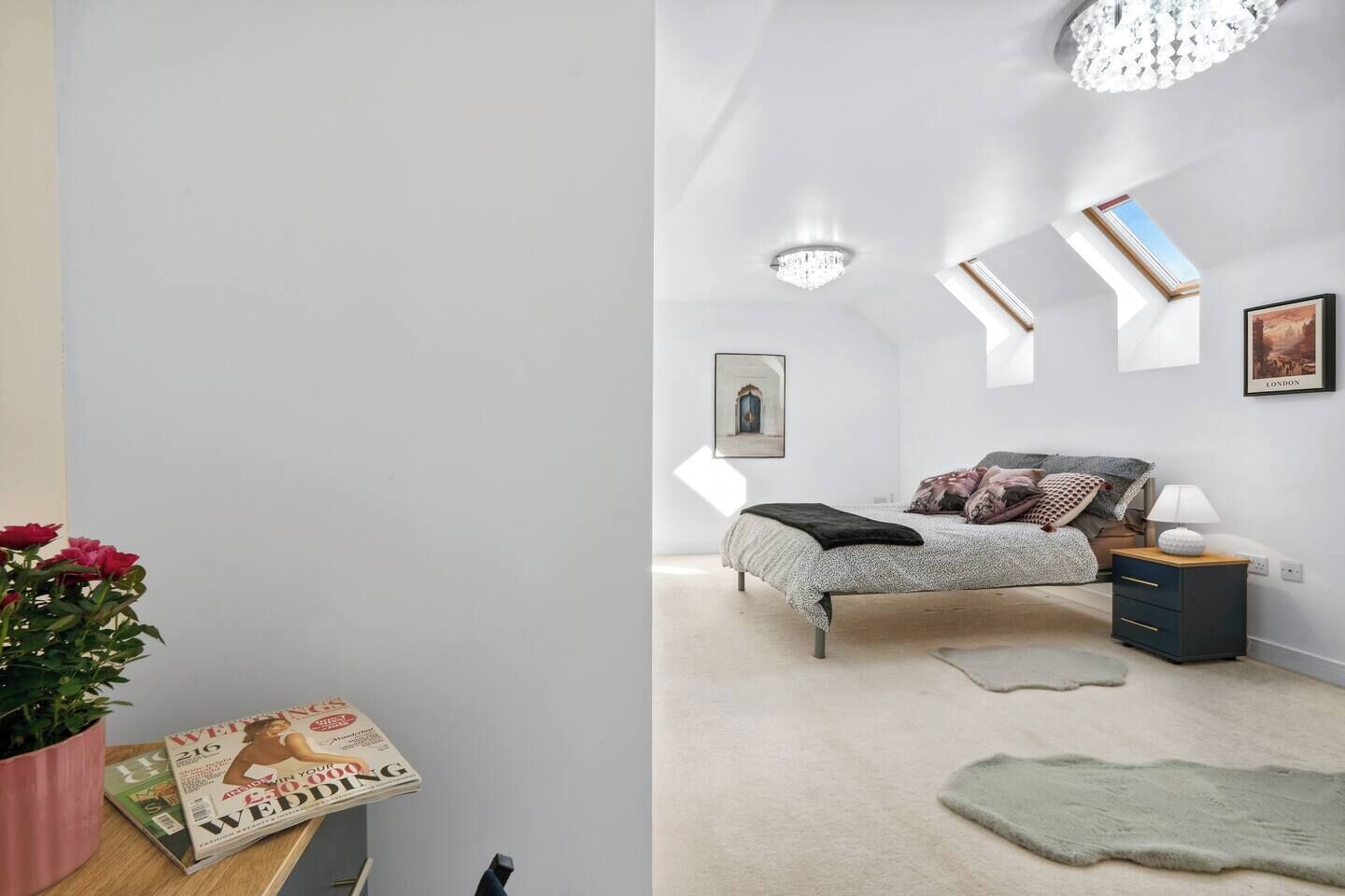 A bedroom with a bed, nightstand, lamp, and a framed picture on the wall.
