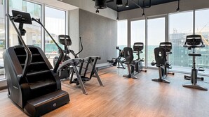 Ein modernes Fitnessstudio mit diversen Trainingsgeräten, großen Fenstern und einer hohen Decke.
