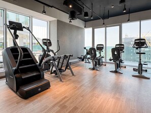 A modern gym with various exercise equipment, large windows, and a high ceiling. - Vogue, Al Wasl Residence Dubai Frame view near World Trade Centre (Dubai)