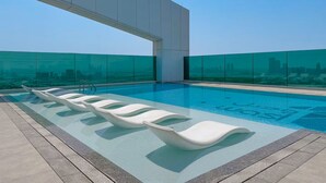 Ein Dachpool mit unendlicher Optik, modernen weißen Liegestühlen und Blick auf die Stadtlandschaft.