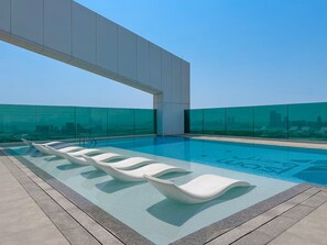 A rooftop infinity pool with modern white lounge chairs and a city skyline view. - Vogue, Al Wasl Residence Dubai Frame view near World Trade Centre (Dubai)