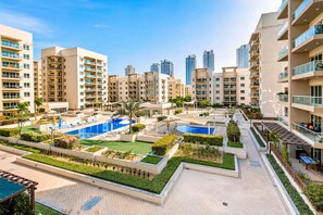 A residential complex with multiple apartment buildings, a swimming pool, and landscaped gardens.