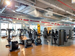 Une salle de sport équipée de tapis de course, de vélos elliptiques et d’appareils de musculation.