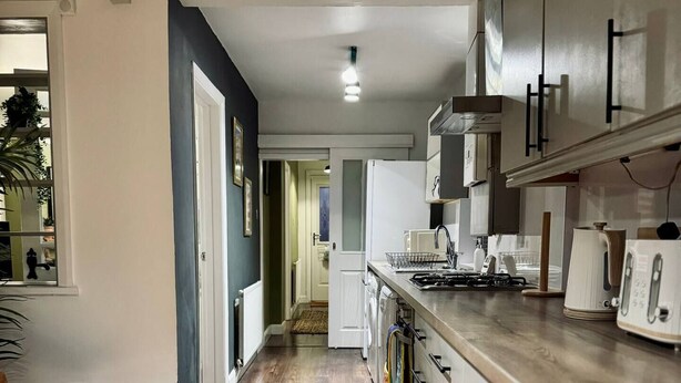 A modern kitchen with a wooden countertop, white cabinets, and a stainless steel range hood. - Strathmore - City centre, close to University (Coventry)