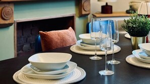 A dining area with a table set for four, a fireplace, and a framed artwork on the wall. - Strathmore - City centre, close to University (Coventry)