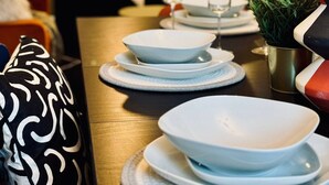 A dining area with a wooden table set for four, white plates, and a small potted plant. - Strathmore - City centre, close to University (Coventry)