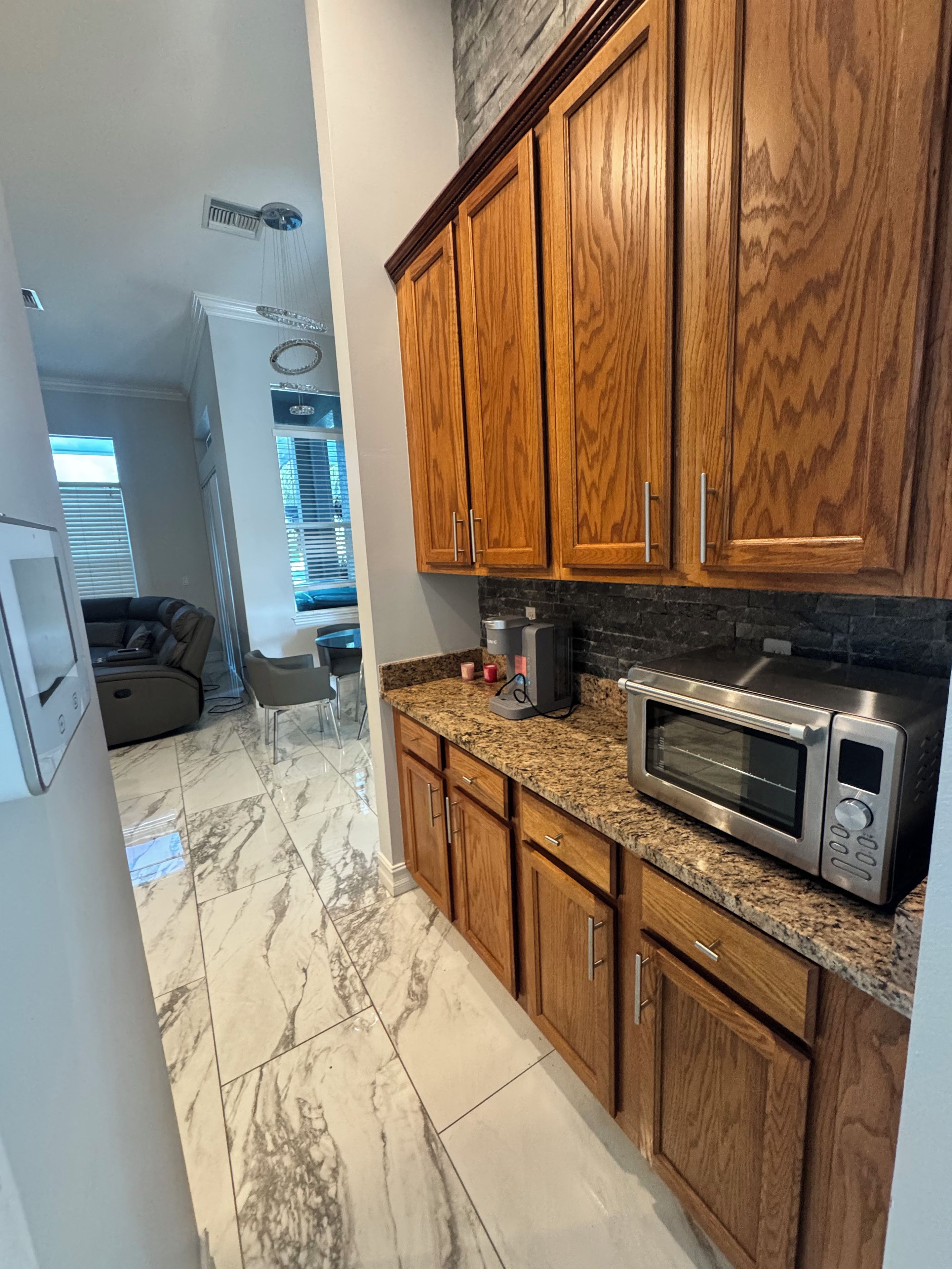 A kitchen with wooden cabinets, a microwave, and a granite countertop.