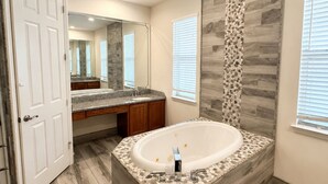 Une salle de bain moderne avec une baignoire sur pieds, un grand miroir et un meuble-lavabo doté d’un plan de travail en granit.