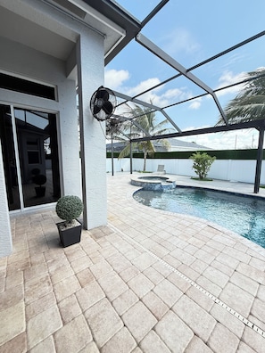 A covered outdoor area with a swimming pool, a potted plant, and a fan.
