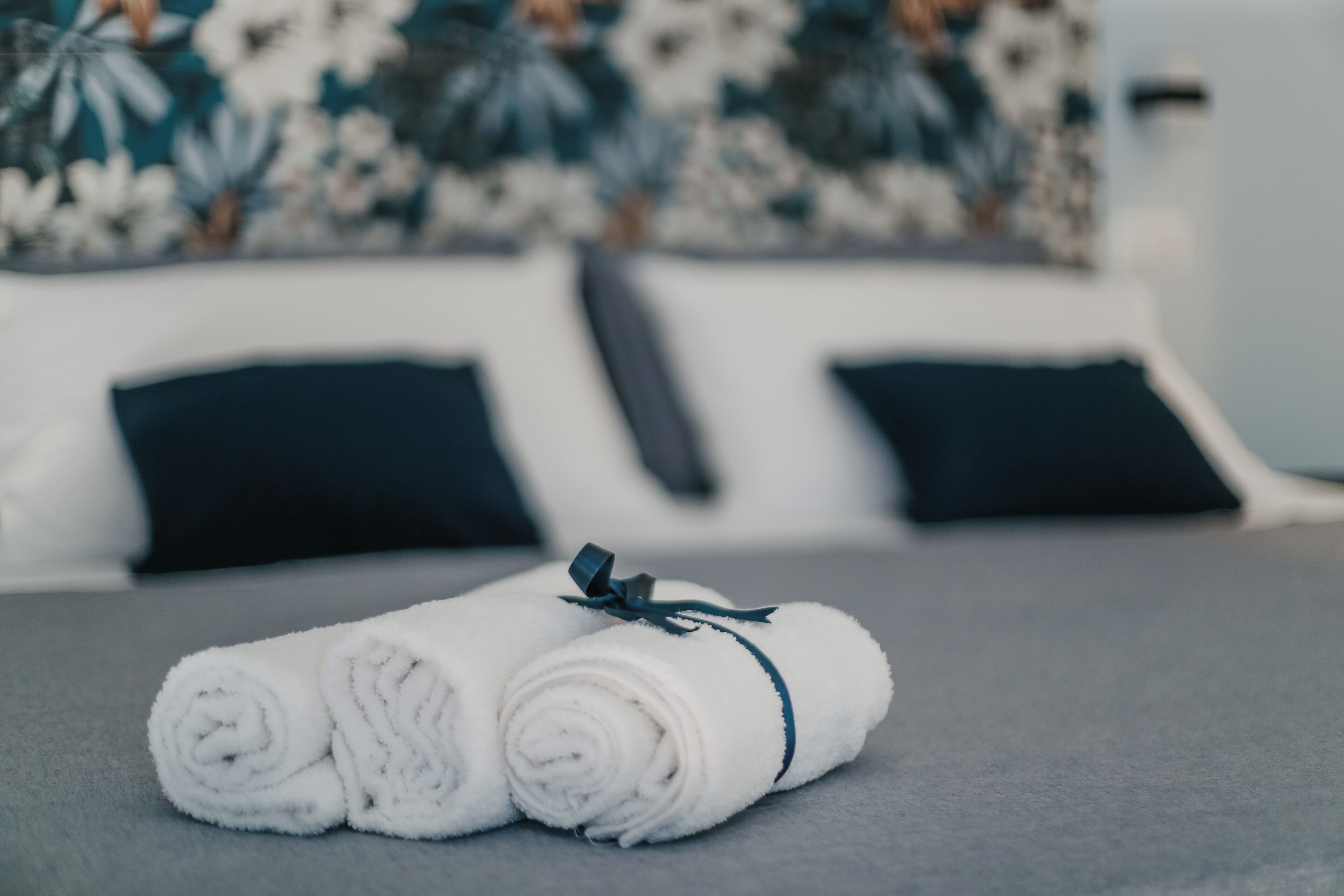 Ein ordentlich bezogenes Bett mit weißen Handtüchern und einer dunkelblauen Schleife.