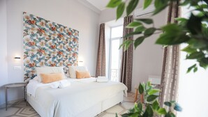 A modern hotel room with a large bed, a decorative wall tapestry, and a view of the outdoors. - DOMUS MARINA Rooms (Naples)