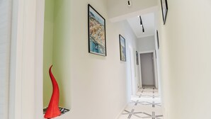 A hallway with a red sculpture, framed artwork, and patterned flooring. - DOMUS MARINA Rooms (Naples)
