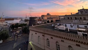A cityscape at sunset with buildings, a harbor, and a clear sky. - DOMUS MARINA Rooms (Naples)