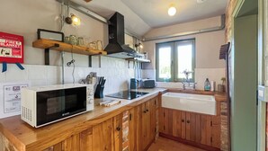Eine Küche mit Holzausstattung, einer Mikrowelle, einem Herd, einem Spülbecken und einem Fenster mit Blick auf Grünflächen.