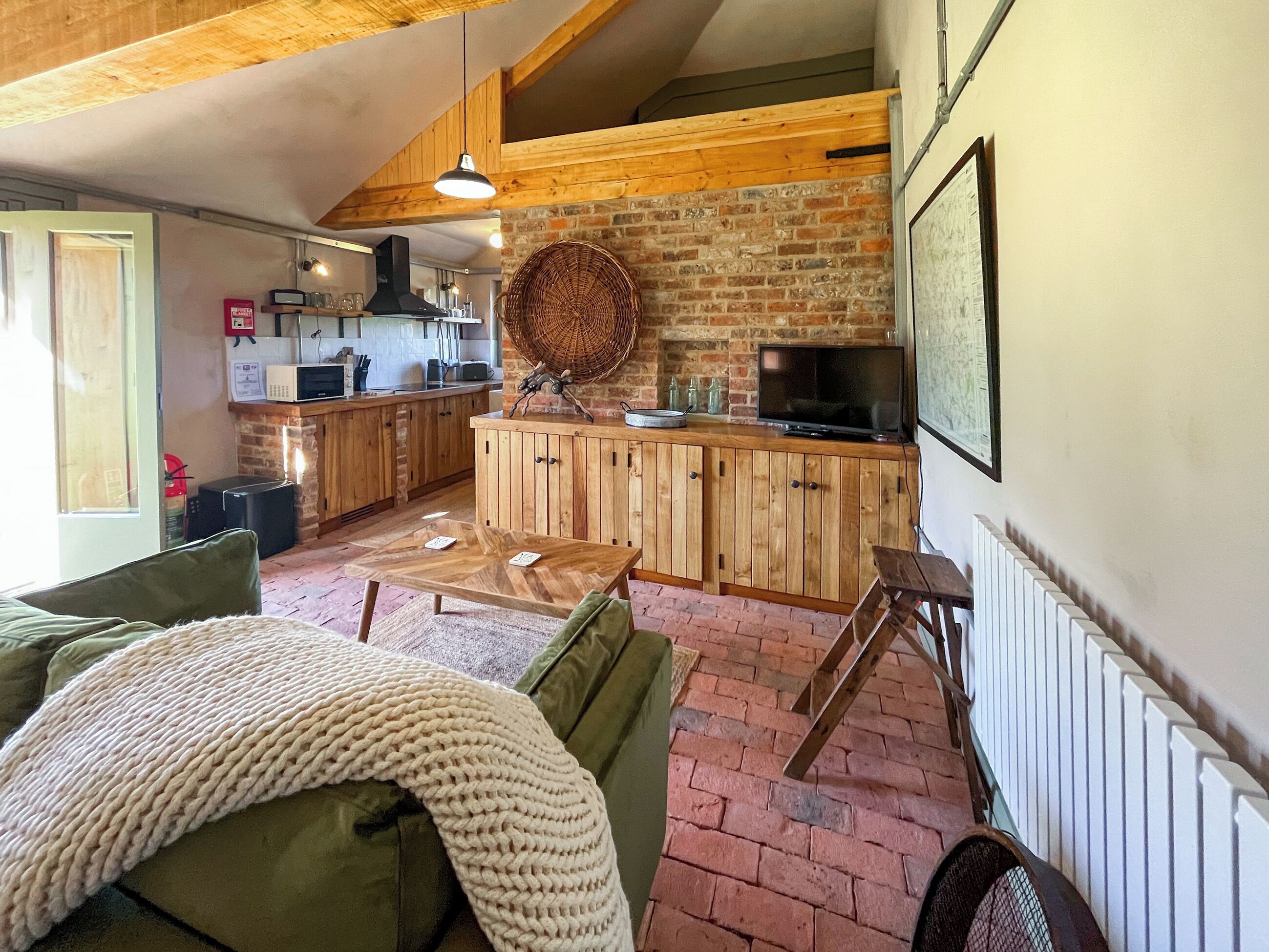 Un salon chaleureux avec un canapé vert, une table basse en bois et un plaid tricoté.