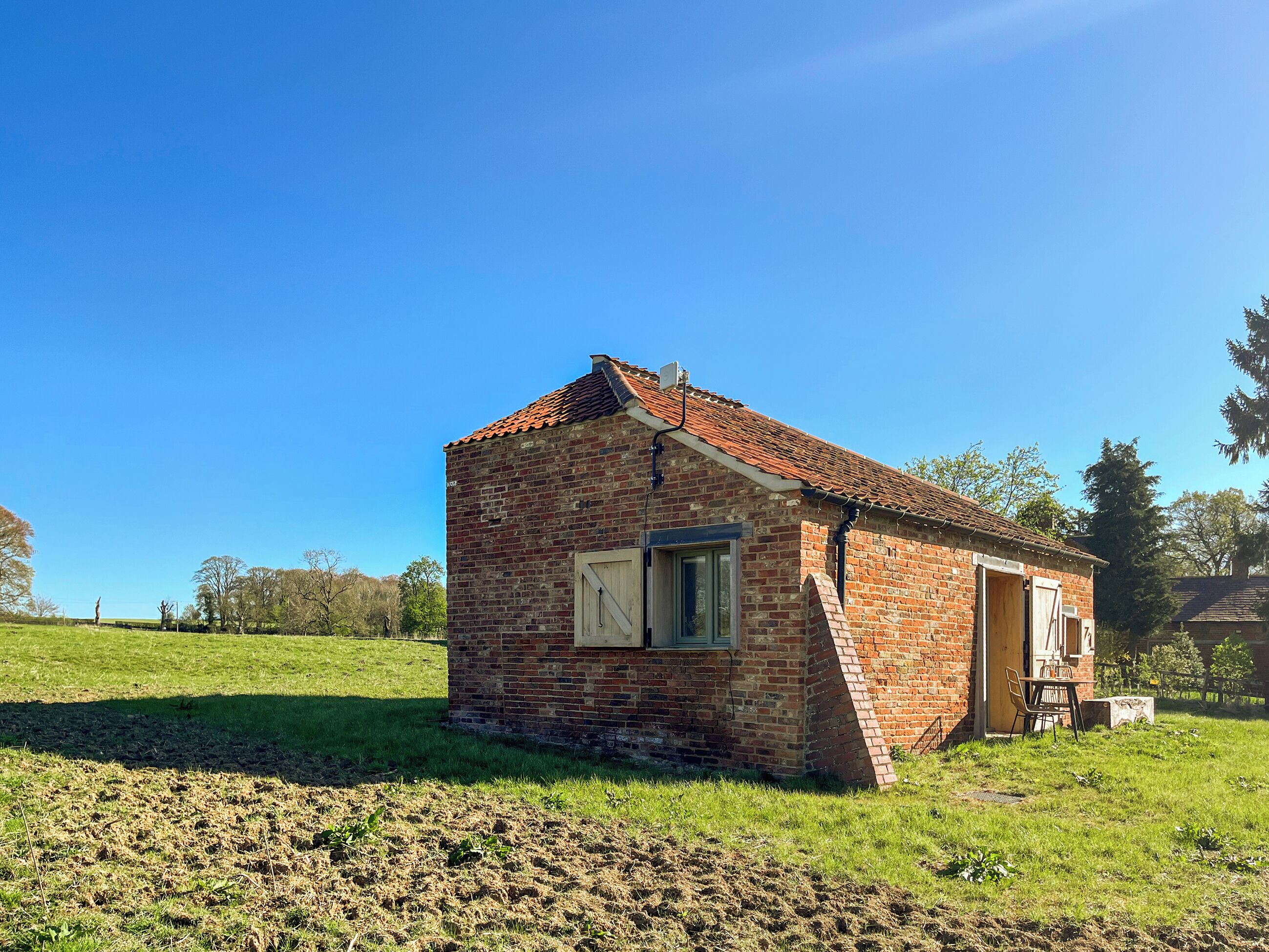 A small brick building with a sloped roof, a single window, and a door.