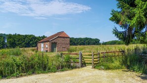Ein rustikales Backsteinhaus mit Ziegeldach, einem Schotterweg und einem Holztor.