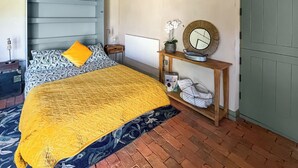 Ein Schlafzimmer mit einem Bett, einem Nachttisch, einem Spiegel und einem Regal mit Pflanze und Korb.