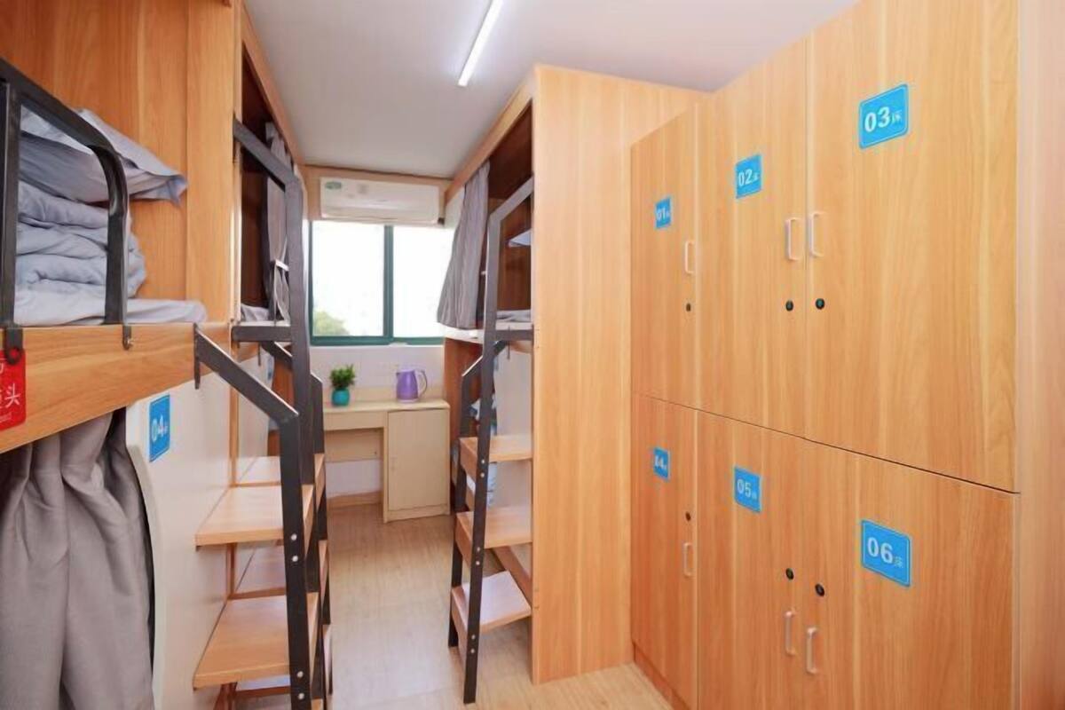 A dormitory room with bunk beds, a desk, and lockers numbered 01 to 06.