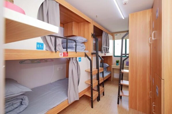 A dormitory room with bunk beds, wooden cabinets, and a small desk with a plant. - Shanghai Xiangyi Hotel (Shanghai)