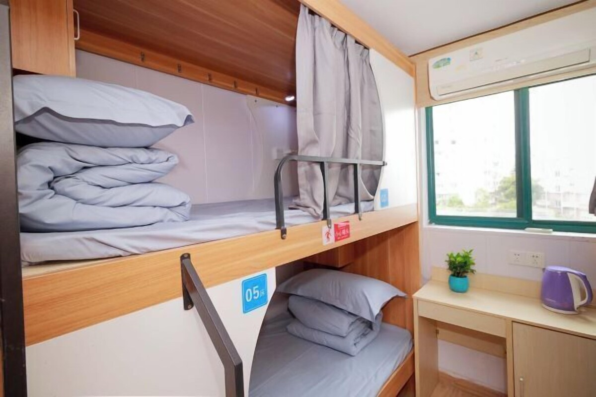 A bunk bed room with a desk and a window.