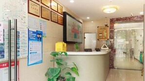 Zona de recepción con mostrador, diplomas enmarcados, un mapa y una planta en maceta.