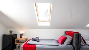 Een moderne slaapkamer met een bed in open loftstijl, een nachtkastje met lamp en een kleine plant.
